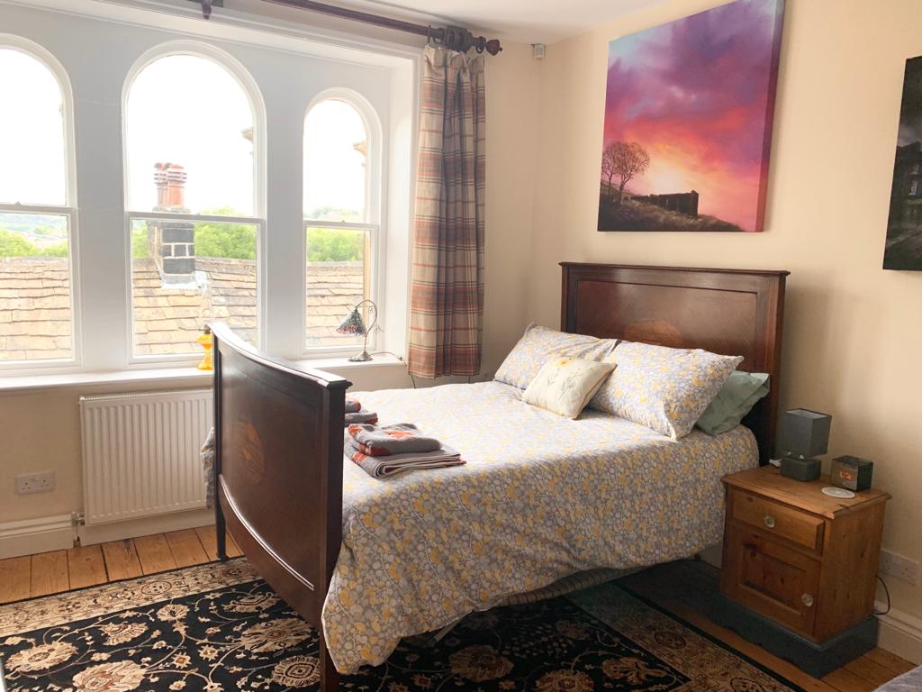 Bedroom with an arched window looking out over Haworth's rooftops